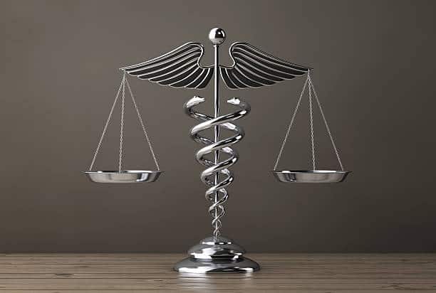 Silver Medical Caduceus Symbol as Scales on a wooden table. 3d Rendering